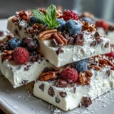 Creamy yogurt base topped with fresh berries and crunchy granola in frozen treat.