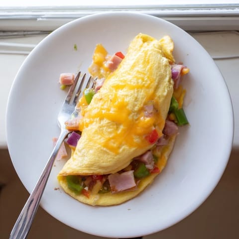 Savory Denver Omelet in a skillet with bell peppers and onions, garnished with fresh herbs and ready to serve with toast.