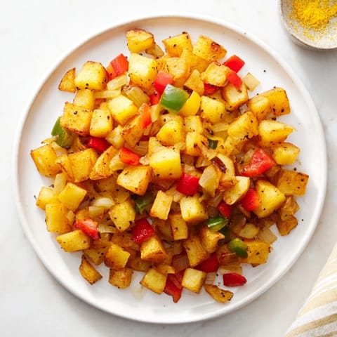 Tender home fries sautéed with onions and peppers, perfect for a hearty American breakfast plate.