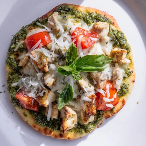 Slice of Chicken Pesto Pizza featuring juicy chicken, basil pesto, and parmesan, served on a white ceramic plate.