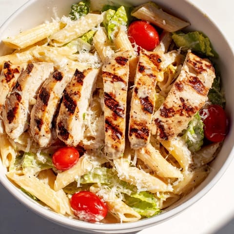 Hearty Spicy Chicken Caesar Pasta bowl topped with golden croutons, fresh parsley, and lemon wedges for serving.