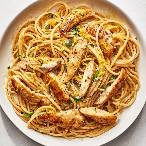 A close-up view of a fork lifting a bite of Brown Butter Lemon Chicken Pasta, showcasing the nutty sauce coating the noodles and juicy chicken strips.