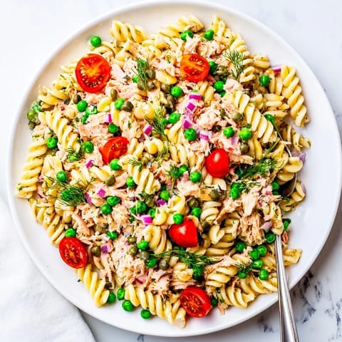 A serving dish of Lemony Tuna Pasta Salad garnished with fresh parsley and dill, perfect for a summer picnic or a light, refreshing lunch.