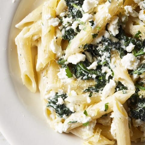 A close-up of Creamy Feta Spinach Pasta showing wilted green spinach and crumbled feta coating the noodles.