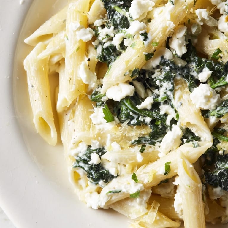 A close-up of Creamy Feta Spinach Pasta showing wilted green spinach and crumbled feta coating the noodles.