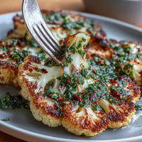 Smoky grilled cauliflower steaks topped with vibrant chimichurri sauce for a bold plant-based meal.  